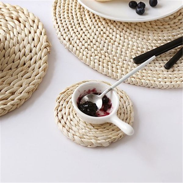 Round woven straw placemats for dining tables, providing heat insulation as pot holders and cup coasters in kitchen settings